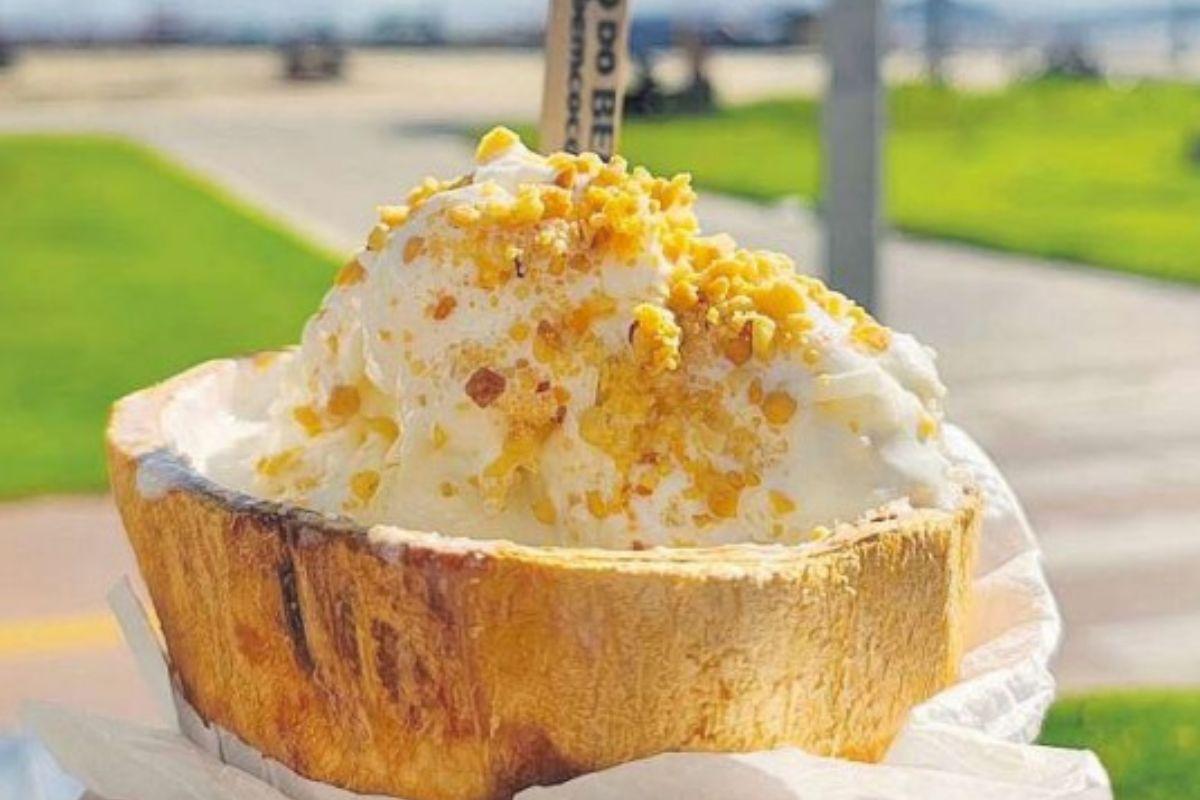 Servido na casca do coco, ele vem com complementos como paçoca