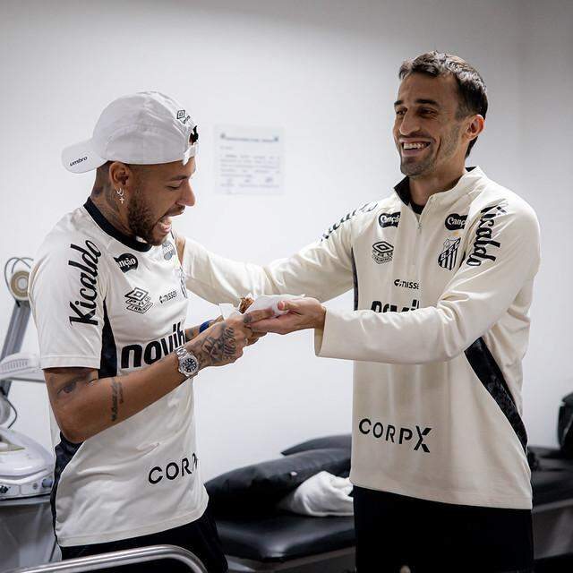 Neymar recebe pedaço de bolo do aniversariante do dia, o volante João Schimdt