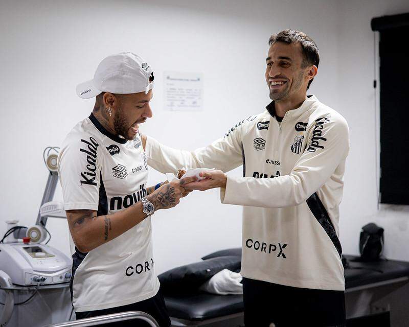 Neymar recebe pedaço de bolo do aniversariante do dia, o volante João Schimdt