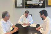 O presidente Marcelo Teixeira assina o acordo, ao lado do representante da Saint-Gobain (à direita)