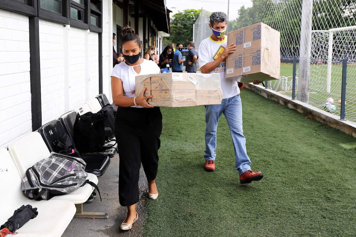 Funcionários do clube carregam caixas com doações