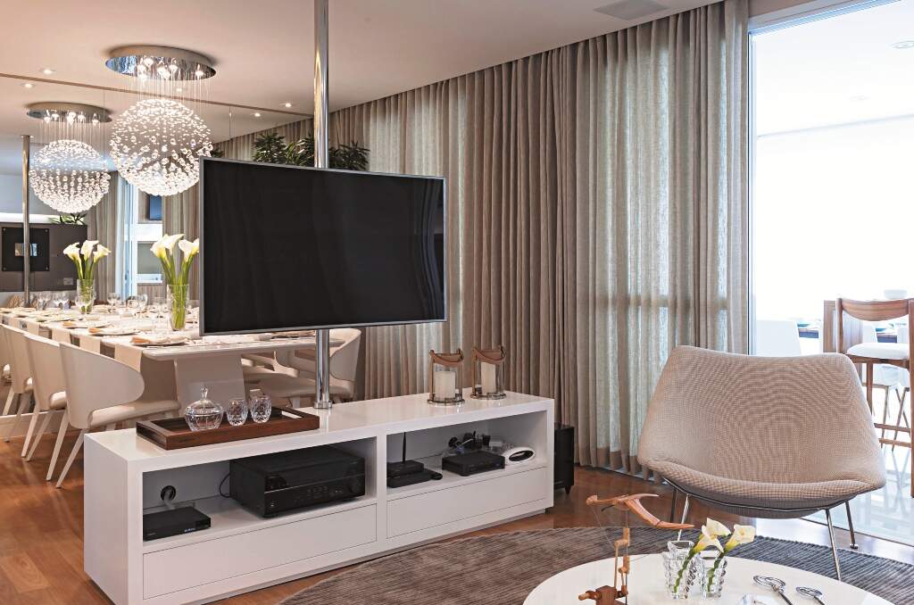 No projeto de Cristiane, suporte giratório faz a TV servir dois ambientes. 