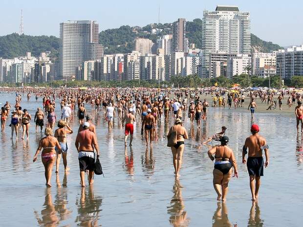 pessoas caminhando na beira do mar em Santos