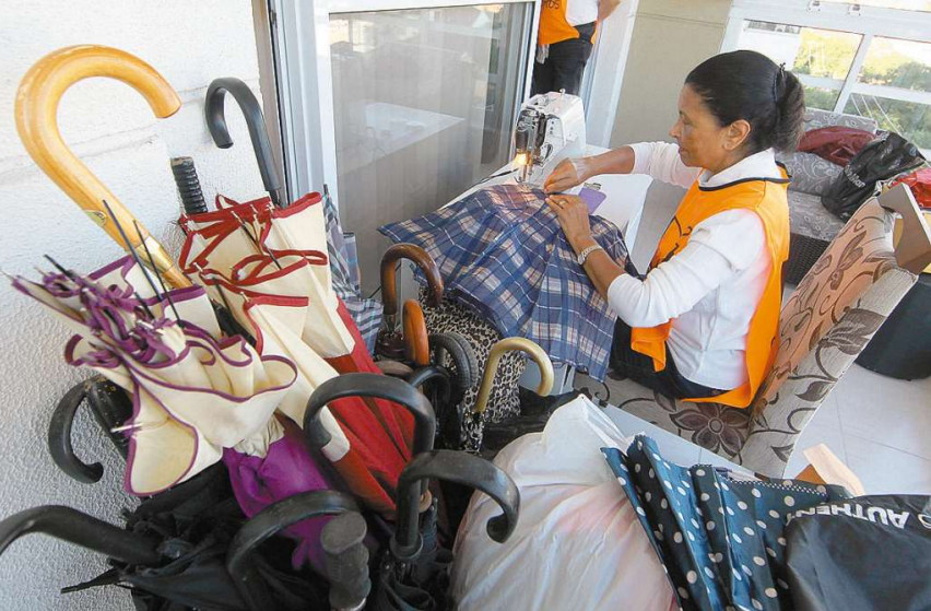 Voluntários fazem a desmontagem de guarda-chuvas e a posterior confecção de sacos de dormir
