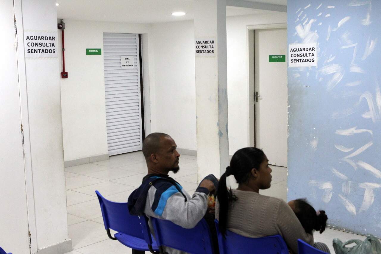 Logo na entrada do PS Infantil de Vicente de Carvalho, uma placa alerta: 'aguarde sentado'
