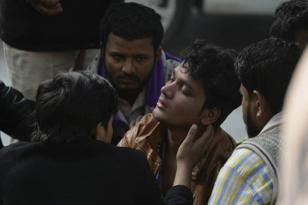 Parentes de vítimas na porta do necrotério, em hospital de Nova Délhi