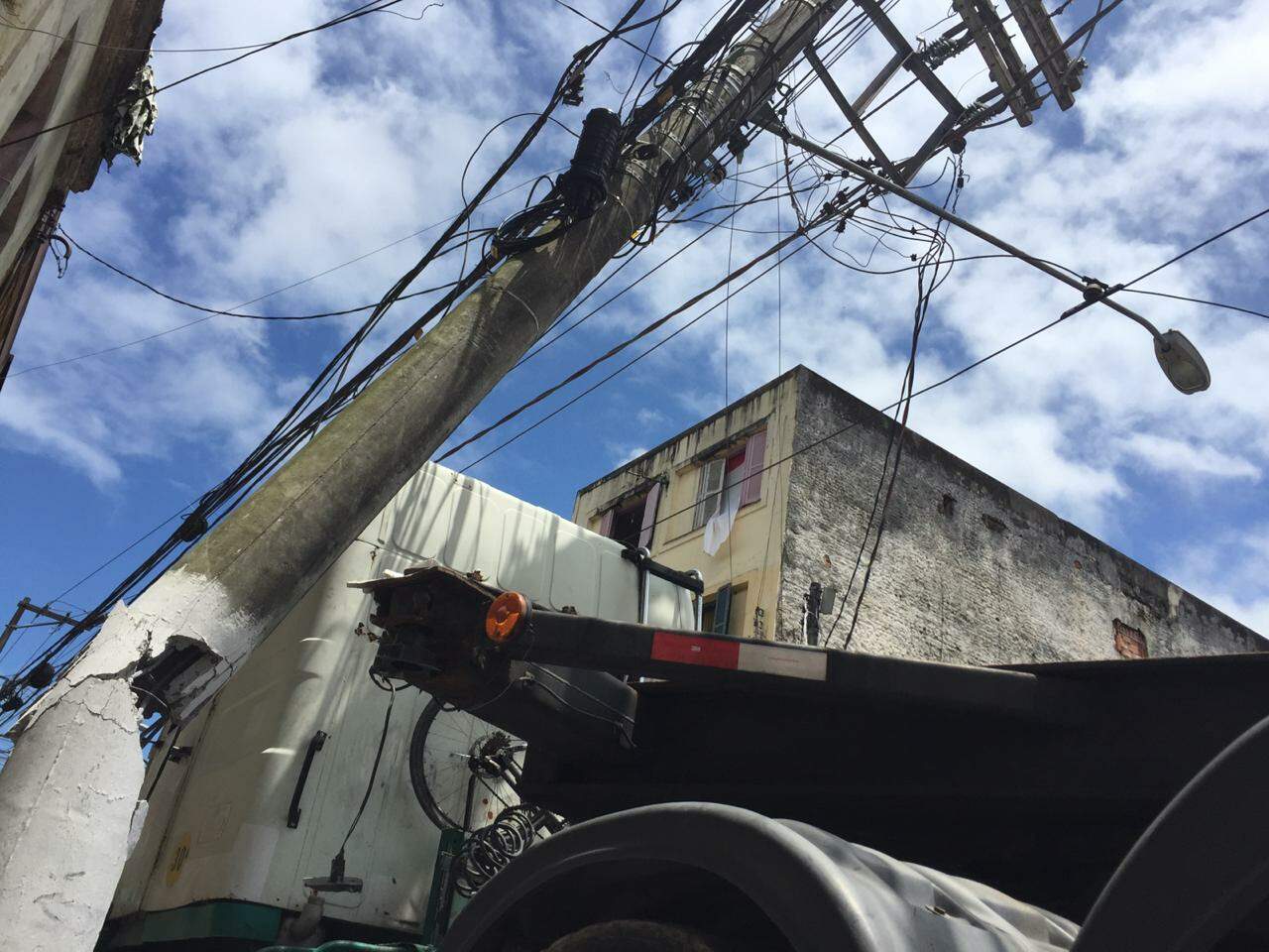 Poste ficou suspenso por cabos de energia na Rua da Constituição, em Santos 
