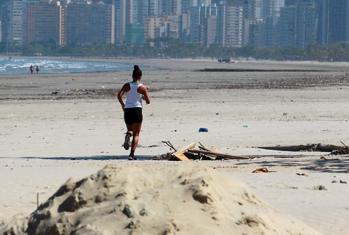 Mulher corre na faixa de areia da praia, em Santos, mesmo com proibição