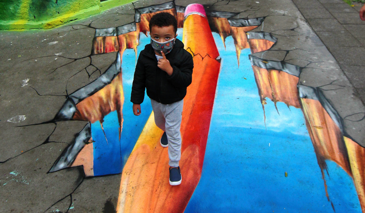 Criança se diverte com pintura tridimensional na calçada 